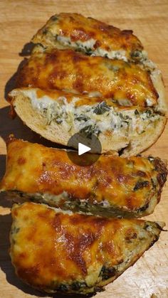 two pieces of bread with cheese and spinach on it sitting on a cutting board