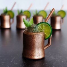 a close up of a drink on a table with mint and limes in it