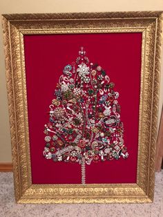 a christmas tree made out of buttons in a gold frame on the floor next to a red wall