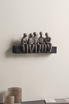 a group of people sitting on top of a shelf next to a vase and book