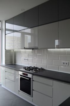 an empty kitchen with white cabinets and black counter tops is seen in this image from the side