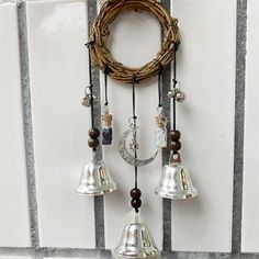 three bells hanging from the side of a wall with a wreath on top of it