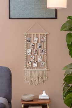 a wall hanging with pictures on it next to a chair and table in a living room