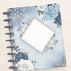 an open notebook with blue roses and gold trimmings on the cover, sitting on a wooden surface