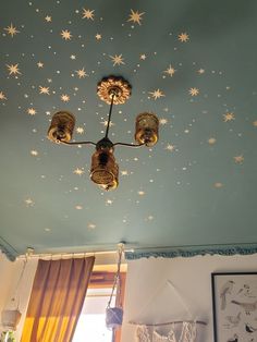 a ceiling with stars painted on it and two lights hanging from the ceiling above them