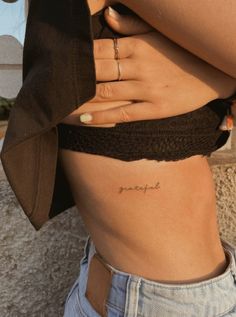 a woman's stomach with the word love tattooed on it