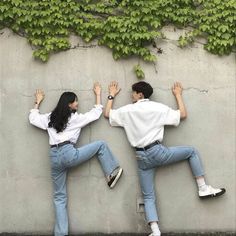 two people standing next to each other with their hands in the air