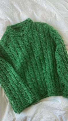 a green sweater laying on top of a bed