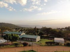 an aerial view of a farm with cars parked in the lot and mountains in the background