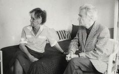 an old photo of two women sitting on a couch talking and looking at each other