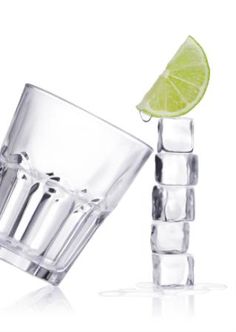 a lime slice sitting on top of a glass next to an ice cubes holder