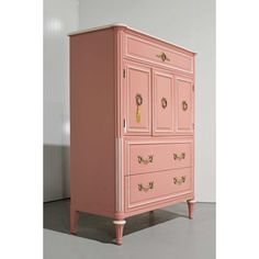 a pink dresser with gold handles and knobs on the doors is shown in an empty room