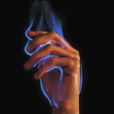 a hand holding something with blue flames coming out of it's palm and fingers