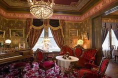 a fancy dining room with red chairs and a chandelier hanging from the ceiling