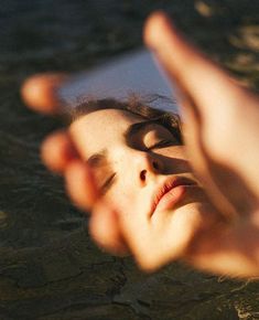 a woman in the water looking at her cell phone while holding it up to her face