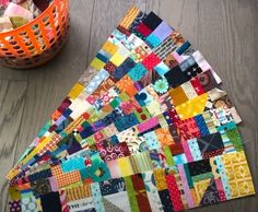 a colorful piece of fabric sitting on top of a wooden floor next to a basket