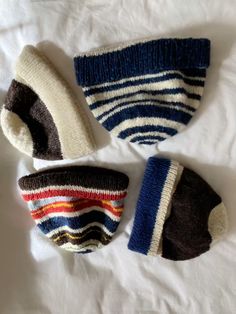 three knitted hats laying on top of a white sheet