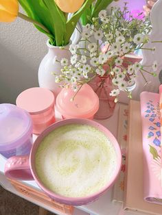 a table topped with lots of pink and white flowers next to cups filled with liquid