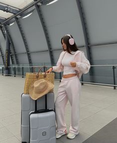 a woman standing next to two pieces of luggage with a straw hat on her head