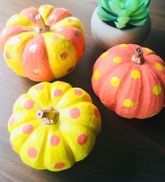 three painted pumpkins sitting on top of a wooden table