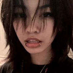 a close up of a person with long hair and piercings on her nose, wearing a black t - shirt