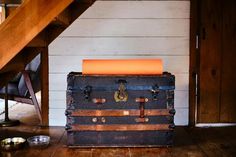 an old trunk is sitting on the floor next to a stair case and dog bowl