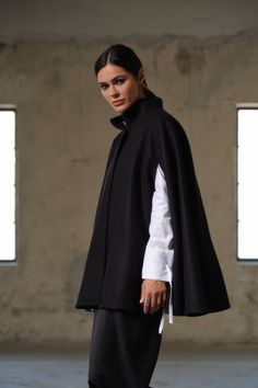 Introducing our Handmade Black Wool Cape - a true masterpiece of craftsmanship, designed to elevate your winter wardrobe to new heights. Meticulously crafted from 100% high-quality sheep wool, this cape is a testament to both warmth and style. With its unique poncho construction, this cape offers a contemporary twist on traditional winter outerwear. It features carefully designed openings for the arms, allowing for freedom of movement without compromising on coziness. The hidden button closure a Black Workwear Poncho Cape, Black Cape Poncho For Work, Black Workwear Cape, Modern Cape For Workwear In Fall, Elegant Black Oversized Cape, Elegant Oversized Black Cape, Modern Fall Cape For Workwear, Oversized Wool Cape Coat For Fall, Oversized Winter Cape For Work