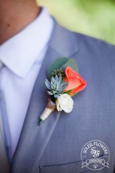 a boutonniere with an orange rose and succulents on it