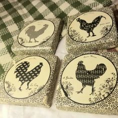 four coasters with chicken designs on them sitting on a tablecloth covered bed spread