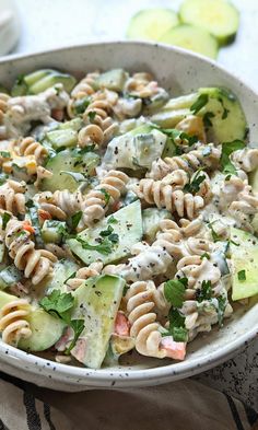 a white bowl filled with pasta salad and cucumbers