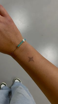 a woman's arm with a small star tattoo on the left side of her wrist