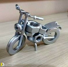 a small metal motorcycle sitting on top of a wooden table next to a bottle opener