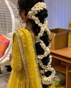 a woman wearing a yellow dress with flowers in her hair and an elaborate braid around her neck