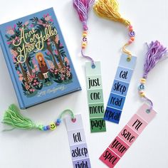 bookmarks with tassels on them sitting next to a book and some beads