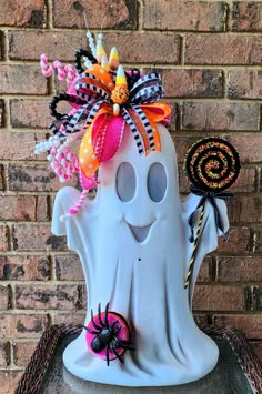 a white ghost with candy and candies on it's head sitting in front of a brick wall