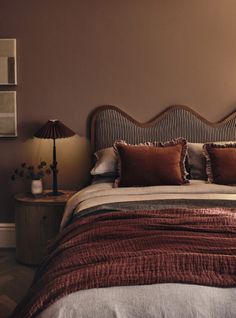 a bed with two lamps on either side of it and a brown wall in the background