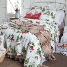 a bed with christmas decorations on it in a bedroom next to a basket filled with pillows