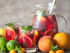 a pitcher and glasses filled with liquid surrounded by citrus fruit on a wooden table - stock photo - images