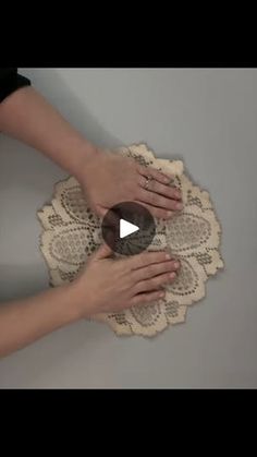 two hands touching each other on top of a doily that is being held by another hand