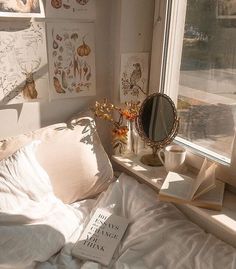 a bed with white sheets and pillows in front of a window next to a book