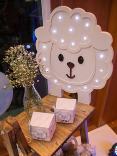 a table topped with boxes and lights next to a teddy bear head on top of a sign