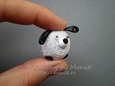 a hand holding a tiny white sheep with black ears