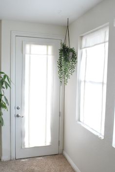 a door with a plant hanging from it's side in front of a window