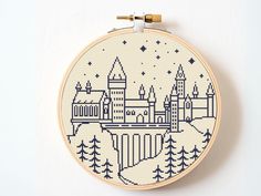 a cross stitch pattern with a castle in the middle and trees around it on a white surface