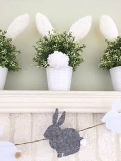 three potted plants with white pom - poms in them on a mantle