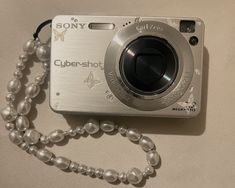 a silver camera sitting on top of a table next to a beaded necklace and bracelet