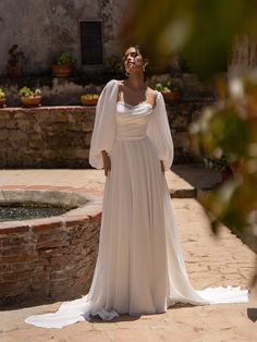 a woman in a white wedding dress standing on a brick walkway next to a fountain