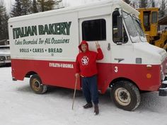 a man standing in front of a red and white truck with italian bakery written on it