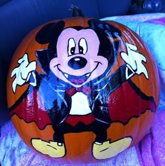 a mickey mouse pumpkin sitting on top of a purple blanket