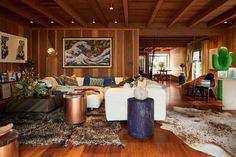 a living room filled with lots of furniture and wood paneled walls on top of a hard wood floor